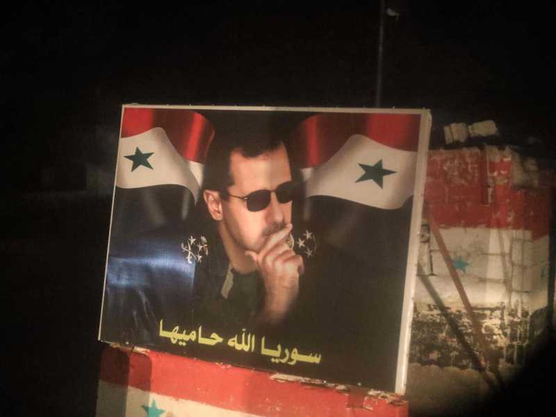 Un manifesto esposto a Ghouta dei sostenitori di Assad (foto LaPresse)