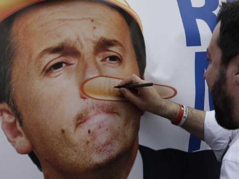 Matteo Salvini autografa un'immagine di Renzi ritratto con il naso di Pinocchio durante una manifestazione a Roma  (foto LaPresse)