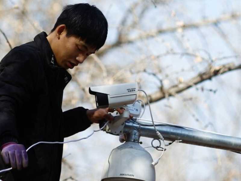 Un operaio monta una videocamera di sorveglianza a Pechino (Reuters/Thomas Peter)
