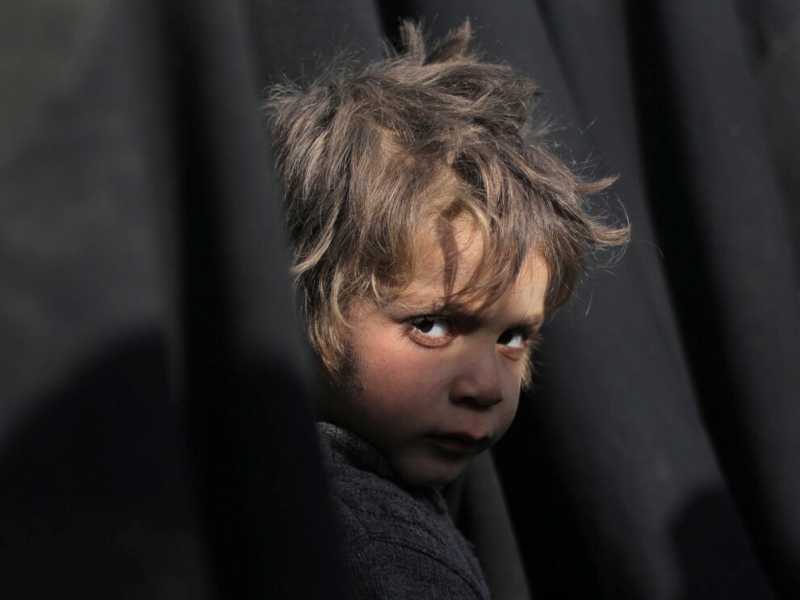 Un bambino esce assieme a una fila di donne dall'ultima enclave dello Stato Islamico in Siria, lo scorso marzo (foto Reuters)