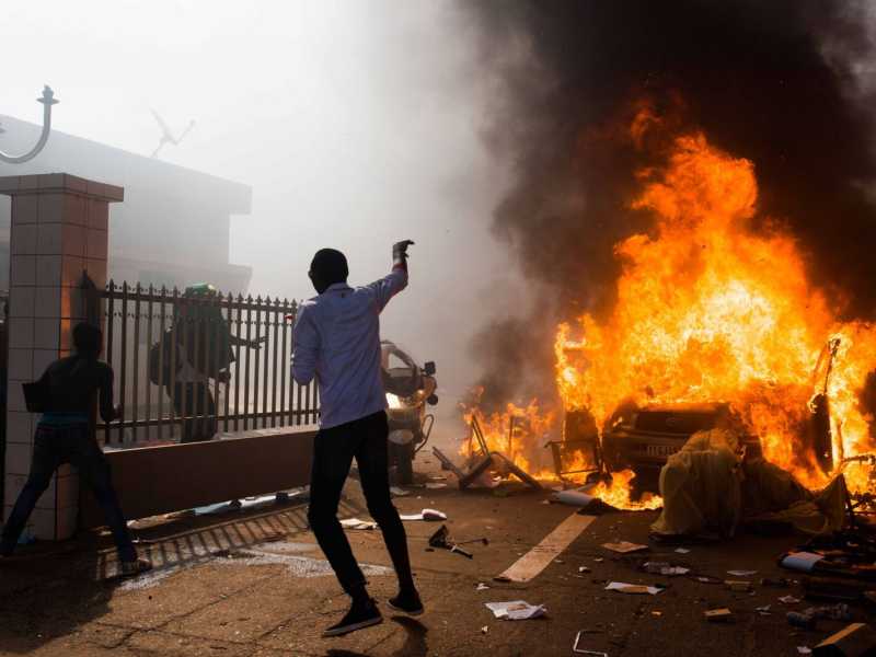 Un'auto in fiamme davanti al Parlamento di Ouagadougou, in Burkina Faso (foto AP)