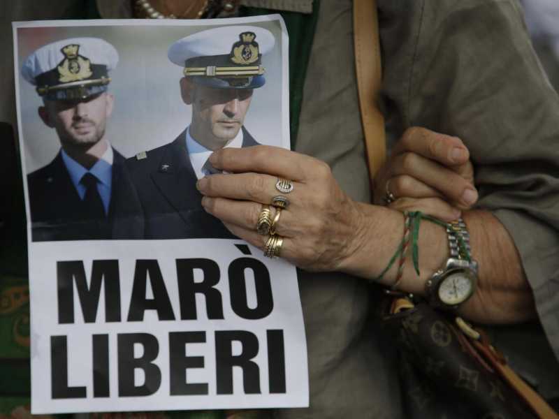 Una donna tiene in mano un volantino per la liberazione dei due mar&ograve; detenuti in India (Foto Lapresse)