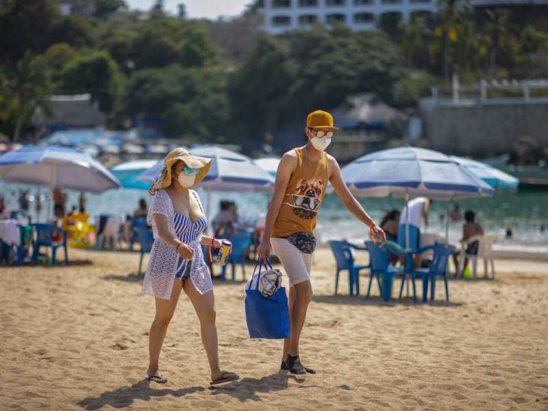 Turisti con la mascherina sulla spiaggia di Caleta il 19 marzo 2021 ad Acapulco, in Messico (foto Hector Vivas/Getty Images)<br />