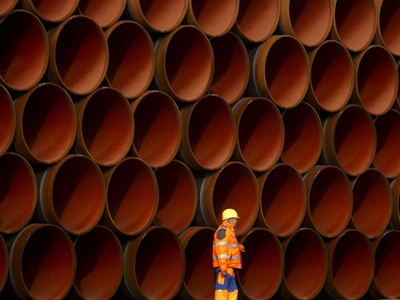 Un lavoratore davanti a tubi accatastati nel cantiere del Nord Stream 2 sull'isola di Ruegen, Germania (foto di Carsten Koall/Getty Images)&nbsp;<br />