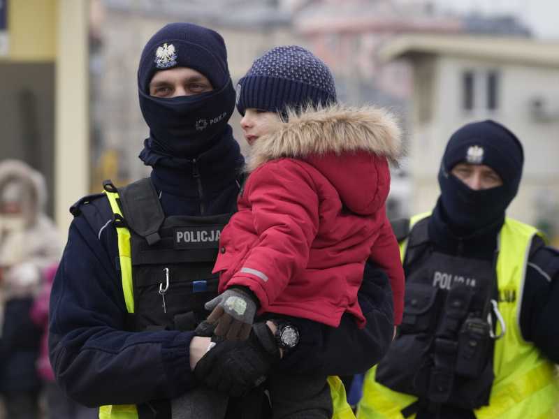 Un ufficiale di polizia con un bambino che arriva in Polonia su un treno da Odesa, in Ucraina (Foto AP/Czarek Sokolowski)&nbsp;<br />