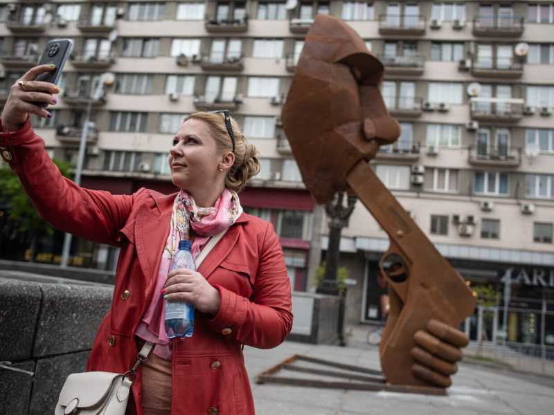 Kyiv, una donna si fa un selfie accanto a una scultura dedicata a Putin, chiamata "Spara a te stesso!" (Alexey Furman/Getty Images)&nbsp;<br />