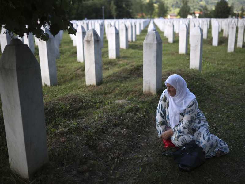 Una donna musulmana inginocchiata al Memoriale di Srebrenica (LaPresse)