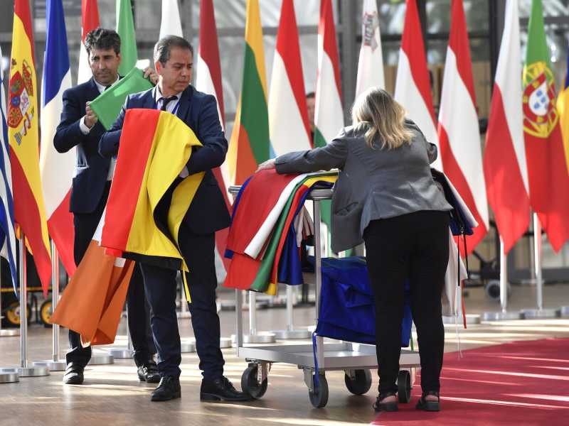 Membri del protocollo issano le bandiere degli stati membri dell'Ue prima di un vertice a Bruxelles (Foto AP/Geert Vanden Wijngaert) <br />