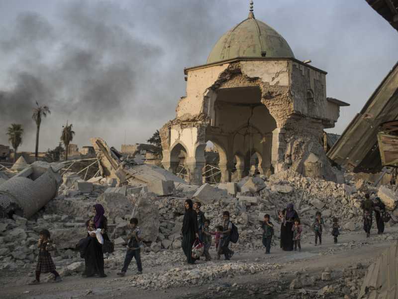 Mosul, luglio 2017: civili iracheni in fuga  nei pressi di una  moschea distrutta durante il conflitto con lo Stato islamico (foto Felipe Dana/Ap)&nbsp;<br />