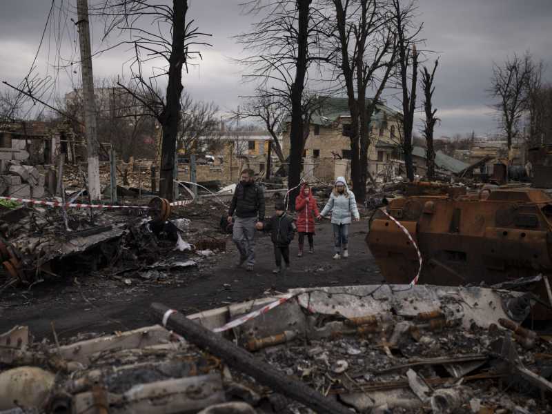 Una famiglia cammina fra le macerie a Bucha, in Ucraina (Lapresse)