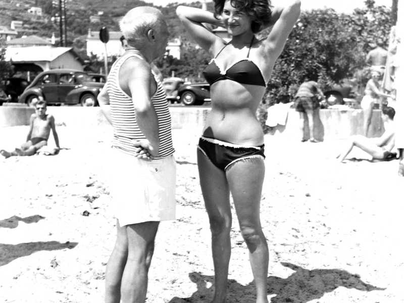 Pablo Picasso fa sorridere una giovane donna sulla spiaggia di Golfe Juan sulla Costa Azzurra francese negli anni '60. (Getty Images) <br />