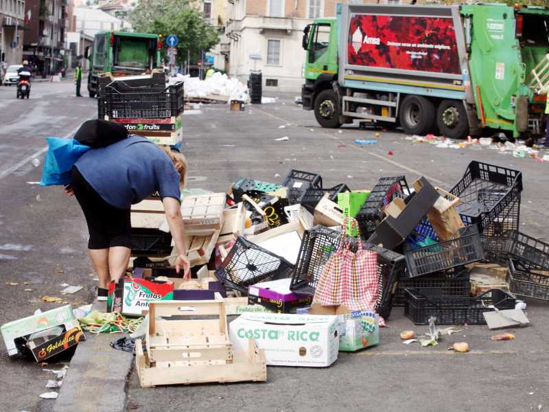 Una donna raccoglie la frutta buttata dopo il mercato di Papignano (MI) - foto LaPresse&nbsp;<br />
