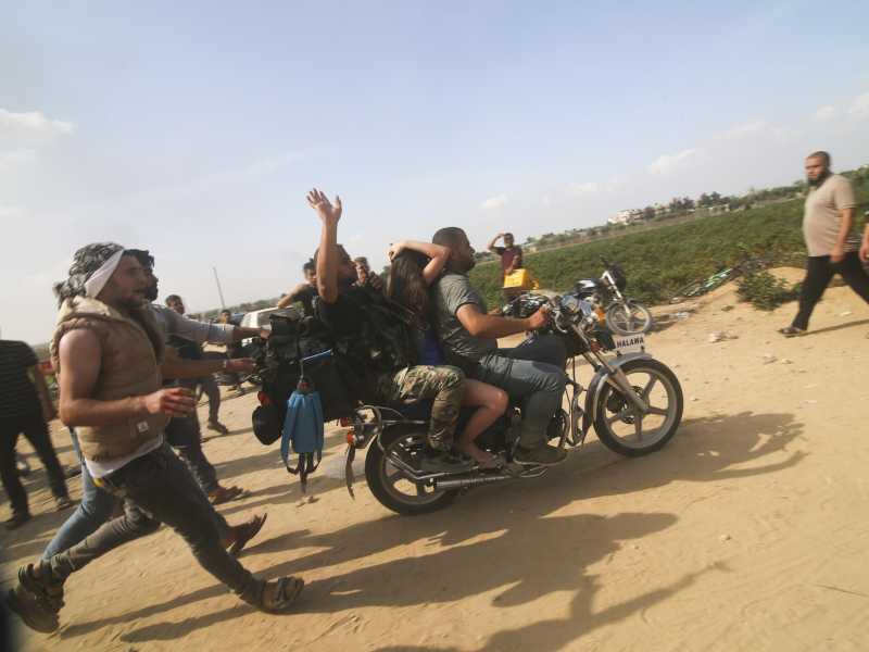 Alcuni militanti di Hamas trasportano un civile israeliano catturato nel kibbutz di Kfar Azza/ Ansa