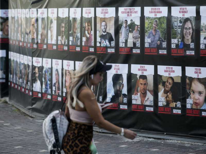 Una donna cammina accanto a manifesti con foto degli ostaggi israeliani nelle mani di Hamas. Hadera, Israele (Amir Levy/Getty Images) 