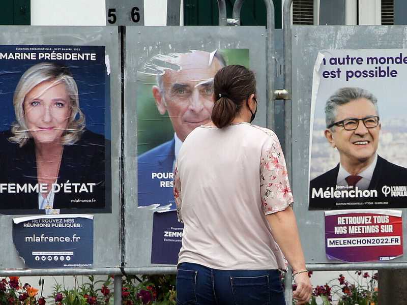 Una donna passa davanti ai manifesti della campagna elettorale (AP Photo/Bob Edme) <br />