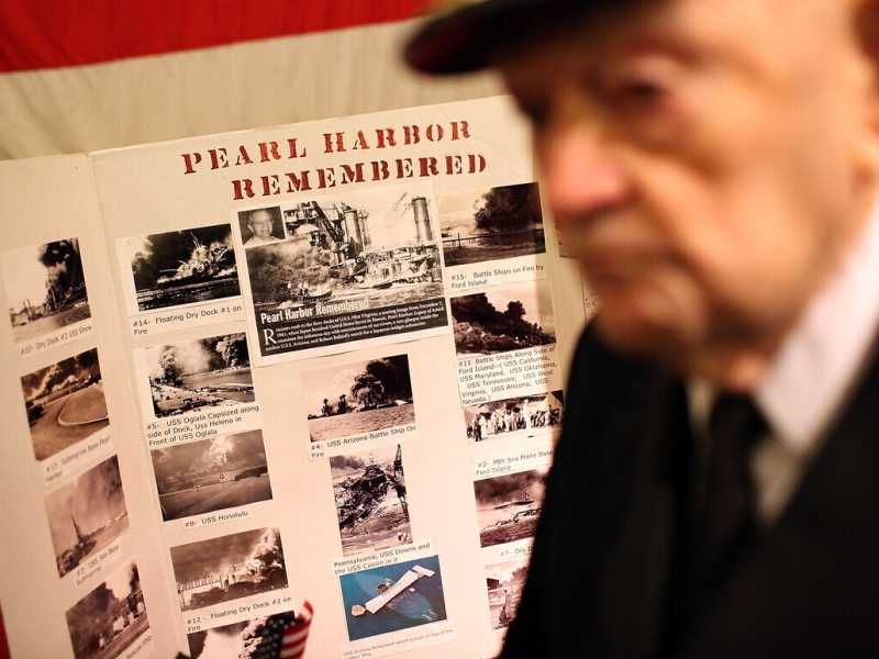 Il cappellano della USS Hornet, John Berger, accanto a un manifesto commemorativo di Pearl Harbor (Justin Sullivan/Getty Images)&nbsp;<br />