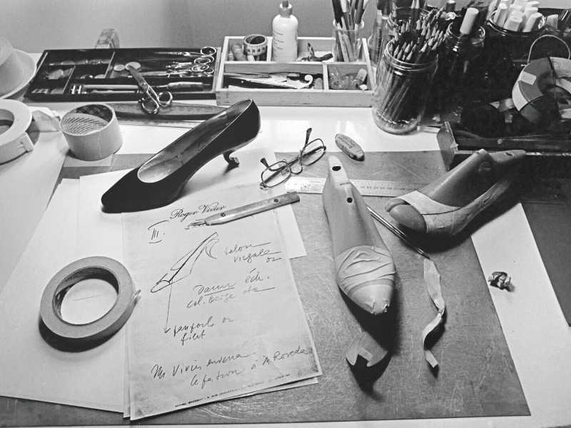 Il tavolo di lavoro di Roger Vivier e un modello di calzatura con il tacco &ldquo;virgule&rdquo; nel suo atelier a Toulouse,&nbsp;nel 1984 (courtesy maison Vivier).