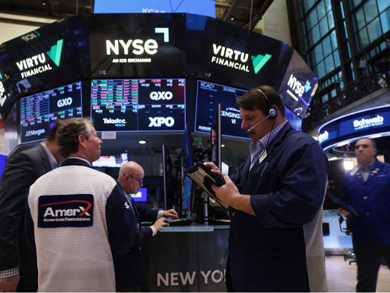 Un trader invia ordini dal suo desk al New York Stock Exchange (foto Getty Images)