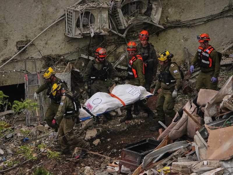 Rescue workers and military personnel carry a body of a victim from the rubble of a residential building a day after it was struck by an Iranian missile in Haifa, Israel, Monday, April 6, 2026. (AP Photo/Ariel Schalit)