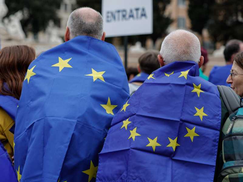 Due anziani avvolti nelle bandiere europee alla manifestazione ‘Una piazza per l’Europa’ a Piazza del Popolo, Roma, 15 Marzo 2025. ANSA/GIUSEPPE LAMI (simbolica, generica)