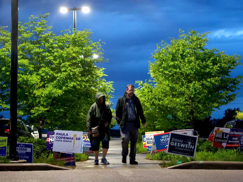Alcune persone passano tra i cartelli davanti a un seggio elettorale durante le elezioni primarie di martedì 5 maggio 2026 a West Lafayette, Indiana (Foto AP/Cara Penquite)